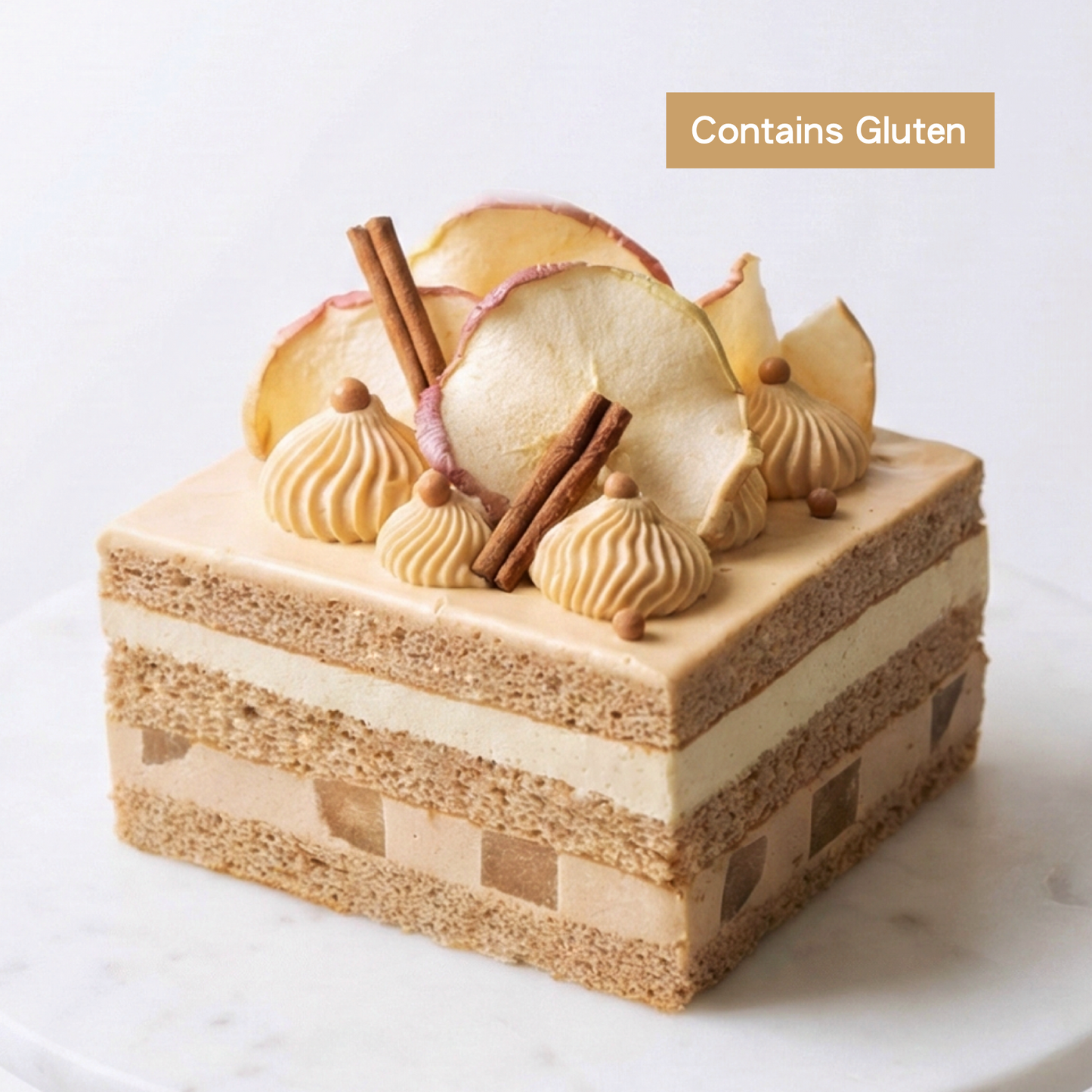 A premium nut-free Apple and Earl Grey Layer Cake beautifully topped with piped caramel, dried apple crisps, and cinnamon sticks, handcrafted by BLUEBUTTER Patisserie in Perth.