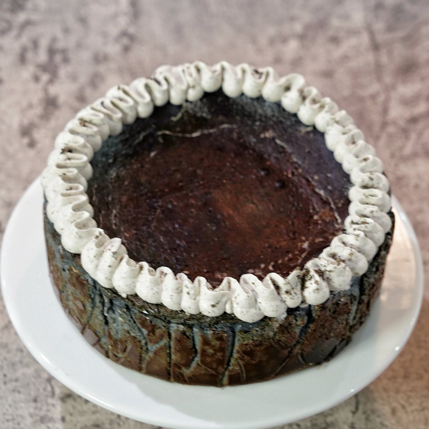 premium gluten-free Black Sesame Basque Cheesecake topped with a delicate ring of sesame cream, handcrafted by BLUEBUTTER Patisserie in Perth.