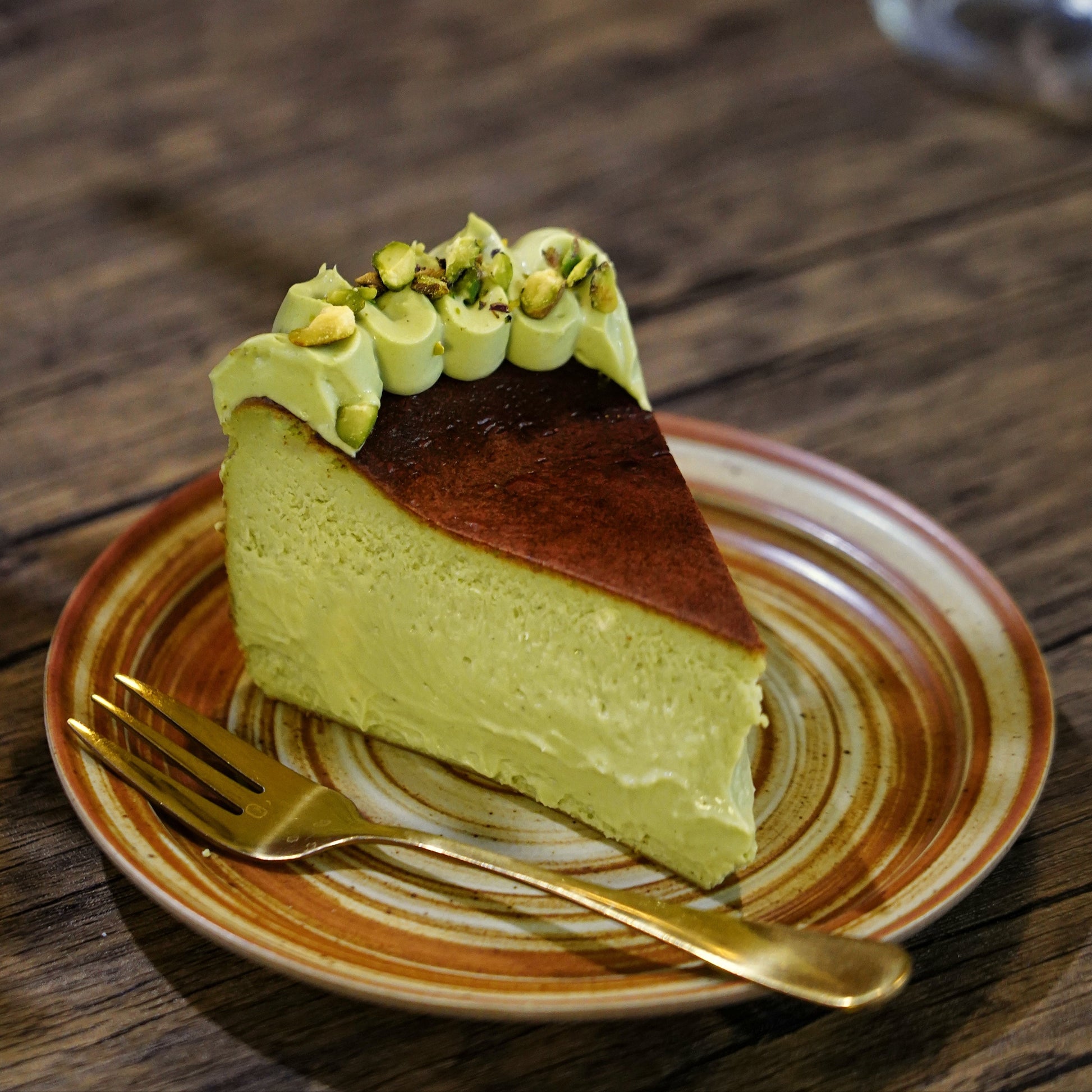 Cross-section of a dense and creamy Pistachio Basque Cheesecake showing its rich green centre and signature caramelised top.