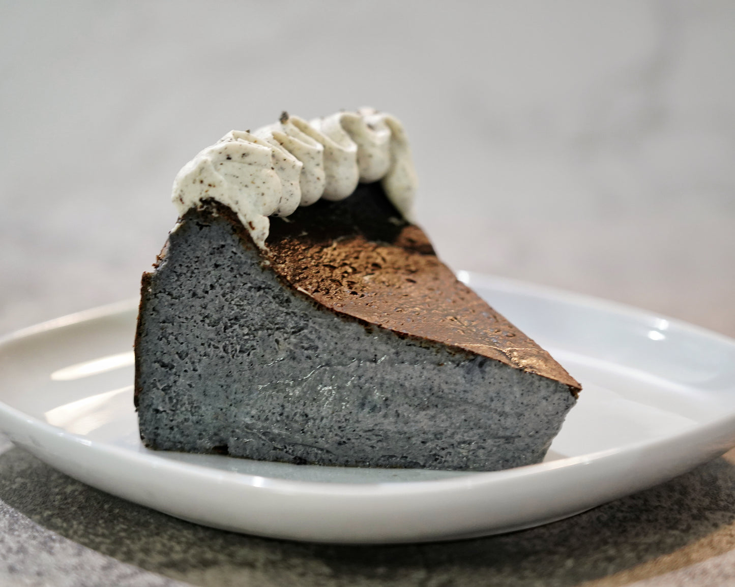 Cross-section of a roasted Black Sesame Basque Cheesecake showing its dark caramelised crust and creamy, mousse-like centre