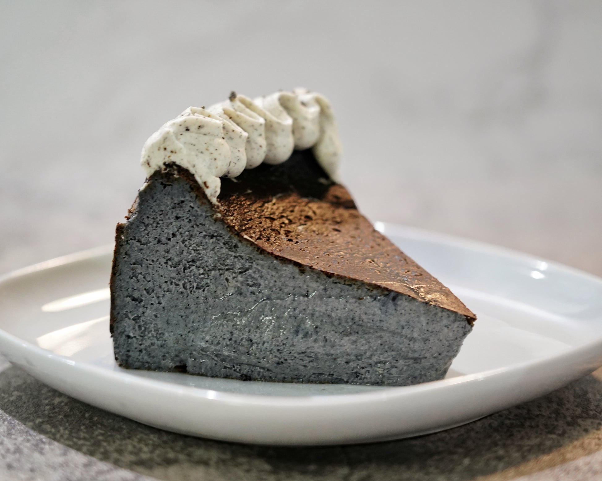 Cross-section of a roasted Black Sesame Basque Cheesecake showing its dark caramelised crust and creamy, mousse-like centre