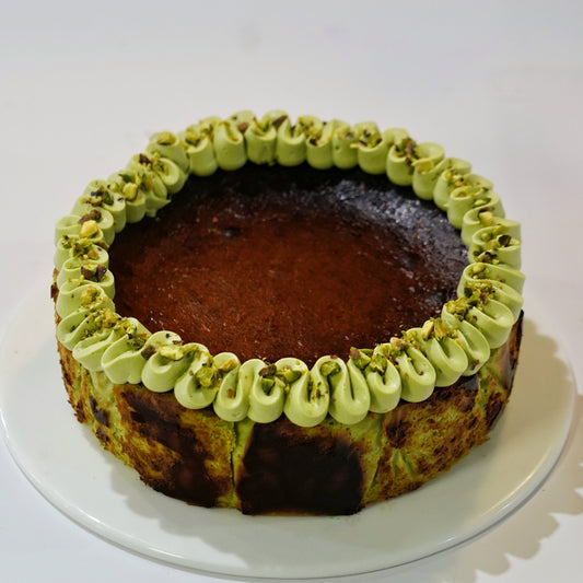 A premium gluten-free Pistachio Basque Cheesecake beautifully topped with smooth pistachio ganache and crushed nuts, handcrafted by BLUEBUTTER Patisserie in Perth.